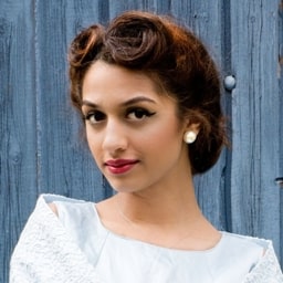 Profile shot of Aiysha Reese, wearing a white dress and taken in front of a grey coloured wooden fence.