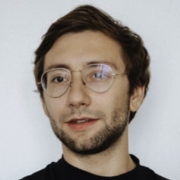 Profile shot of Griffin Wise, wearing a black round neck top and taken in front of a plain white wall.