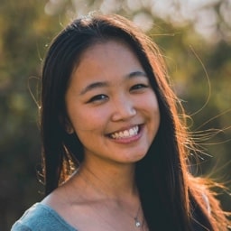 Profile shot of Nikita Marks, wearing a tealed coloured top and taken with a blurred backdrop of a tree.